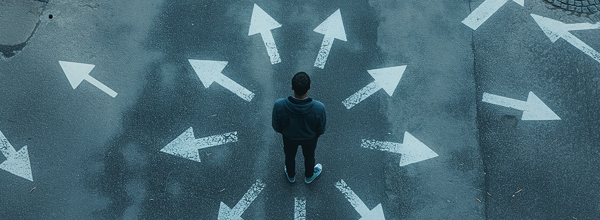 A man standing with arrows painted on the ground in different directions.