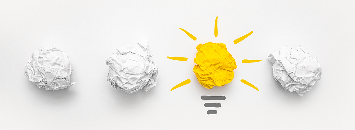 A lightbulb made of paper surrounded by wadded up paper.