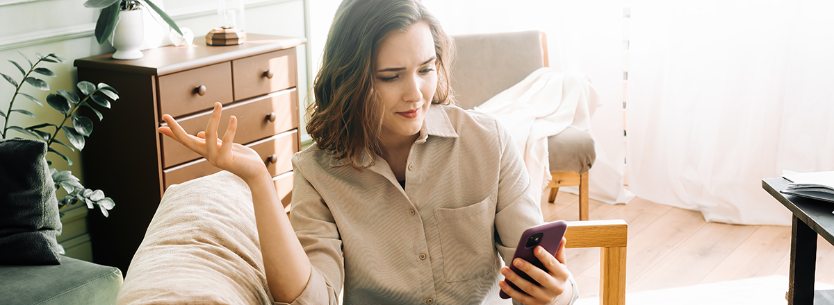 Frustrated woman reacts to something on her phone.